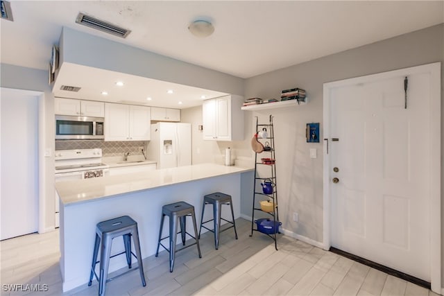 3 Bob O Link Ct Unit 3B, Naples, FL 34105 - kitchen featuring a kitchen bar, kitchen peninsula, white appliances, sink, and white cabinets