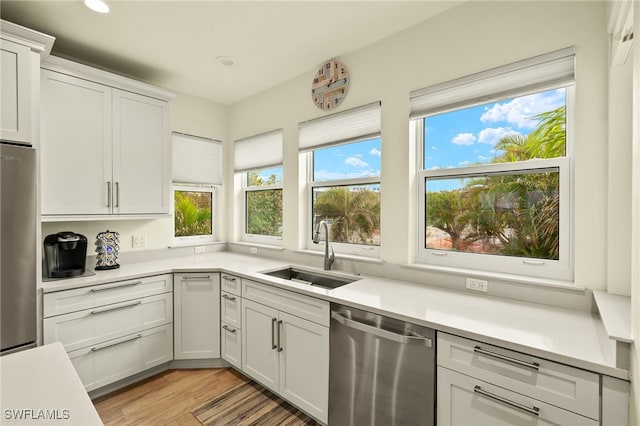 kitchen with white cabinetry, sink, appliances with stainless steel finishes, and light hardwood / wood-style flooring