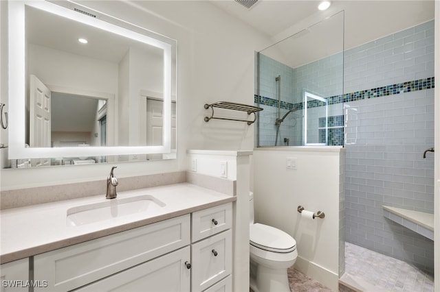 bathroom with tiled shower, vanity, and toilet