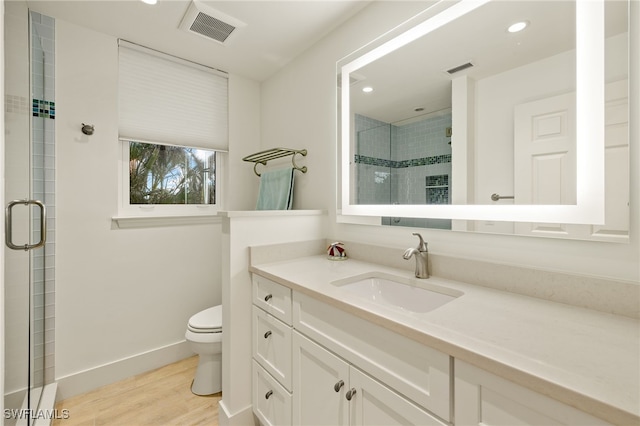 bathroom with vanity, wood-type flooring, a shower with shower door, and toilet