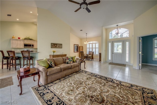 tiled living room with high vaulted ceiling and ceiling fan with notable chandelier