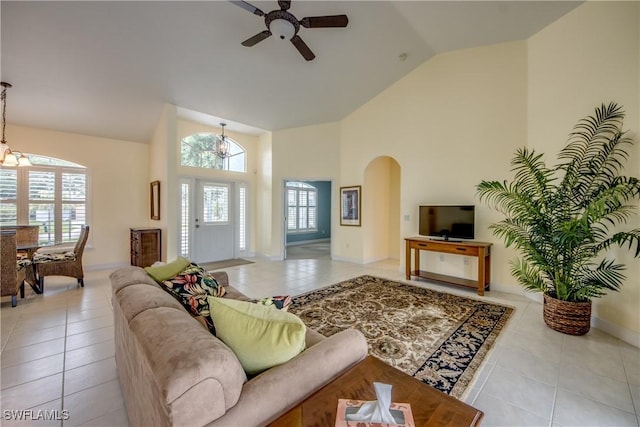 tiled living room featuring high vaulted ceiling, ceiling fan with notable chandelier, and a wealth of natural light