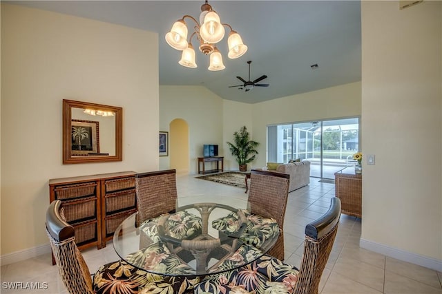 dining space with ceiling fan with notable chandelier, light tile patterned floors, and vaulted ceiling