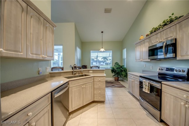 kitchen featuring sink, vaulted ceiling, light tile patterned floors, light brown cabinetry, and appliances with stainless steel finishes