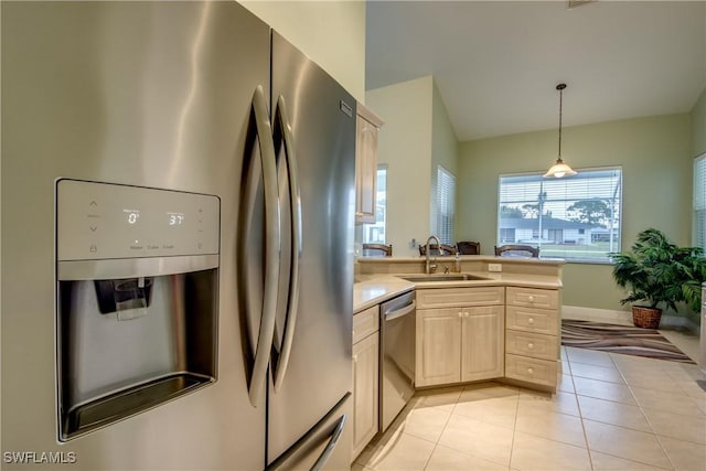 kitchen featuring appliances with stainless steel finishes, light tile patterned floors, hanging light fixtures, and sink