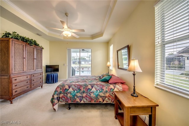 carpeted bedroom with ceiling fan, access to exterior, a tray ceiling, and multiple windows