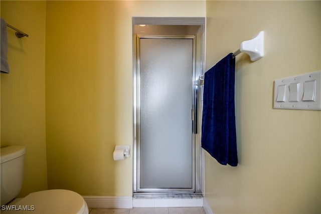 bathroom with tile patterned floors, a shower with shower door, and toilet