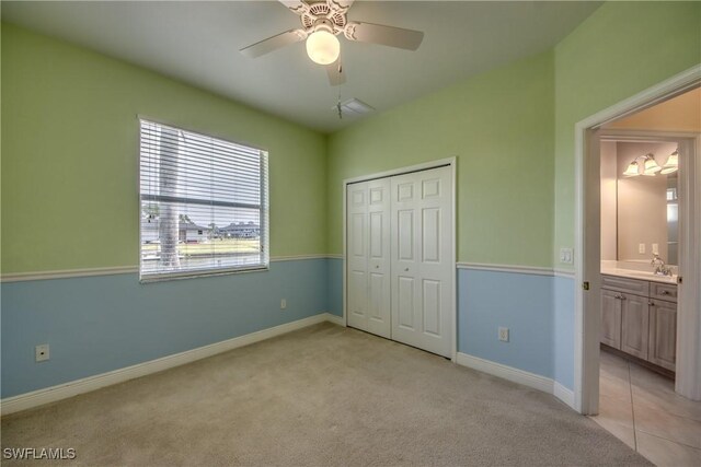 unfurnished bedroom with connected bathroom, ceiling fan, sink, light carpet, and a closet