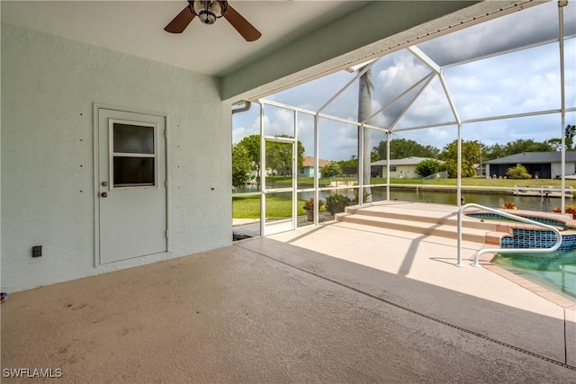 view of patio / terrace featuring glass enclosure, ceiling fan, a swimming pool with hot tub, and a water view