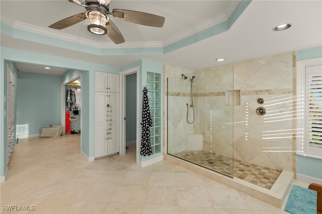 bathroom featuring a tray ceiling, crown molding, ceiling fan, and a tile shower