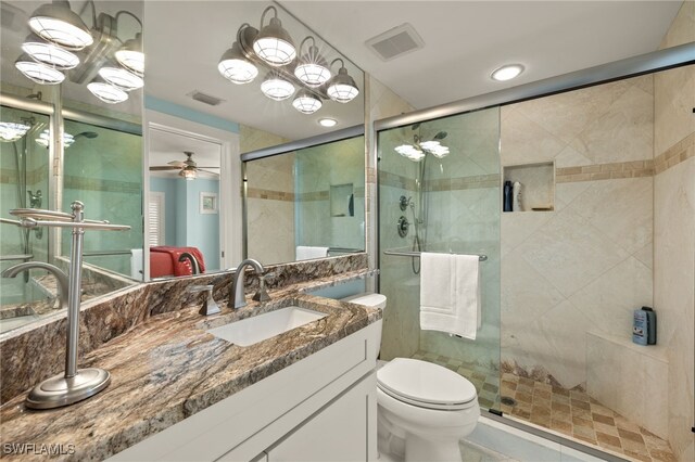 bathroom with ceiling fan, toilet, an enclosed shower, and vanity