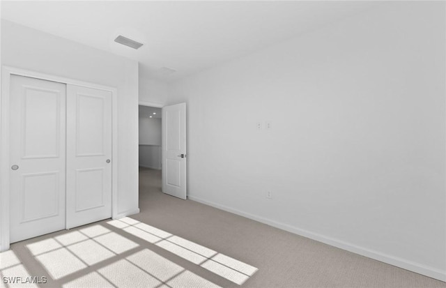 unfurnished bedroom with light carpet and a closet