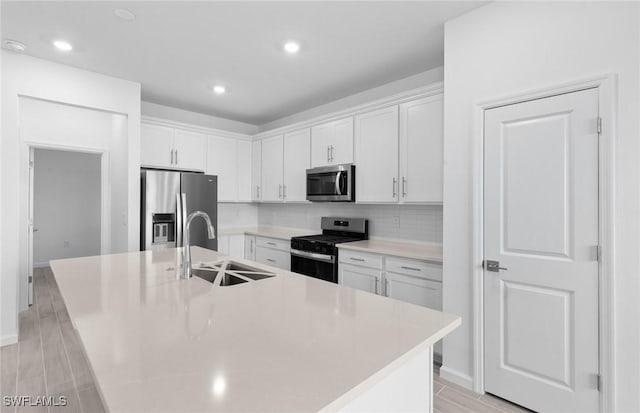 kitchen with sink, white cabinetry, stainless steel appliances, and a kitchen island with sink