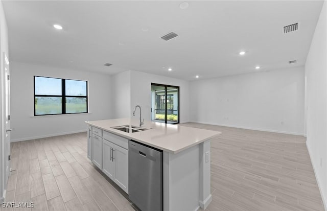 kitchen featuring a wealth of natural light, dishwasher, an island with sink, and sink