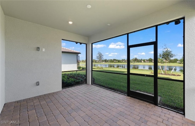 unfurnished sunroom featuring a water view