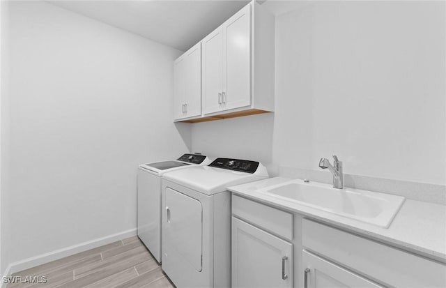 laundry area featuring sink, light hardwood / wood-style flooring, cabinets, and independent washer and dryer