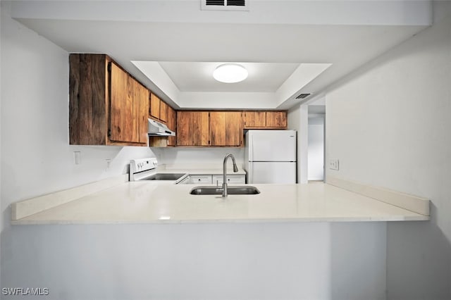 kitchen with kitchen peninsula, range with electric cooktop, a raised ceiling, sink, and white refrigerator