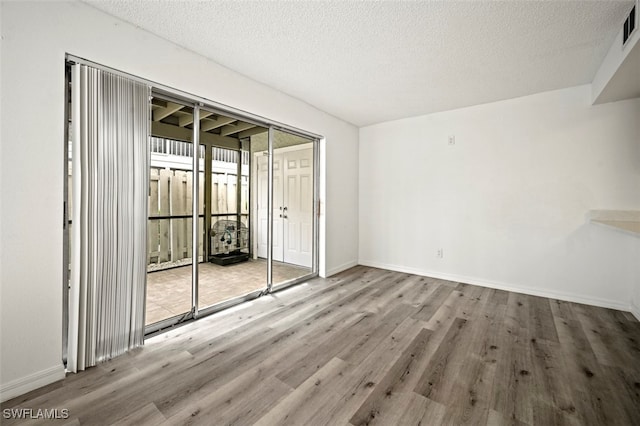 empty room featuring a textured ceiling and light hardwood / wood-style flooring