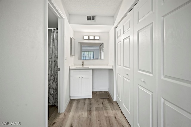 hallway featuring a textured ceiling, sink, and light hardwood / wood-style flooring