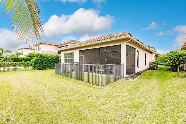 rear view of property with a yard, a water view, and a sunroom