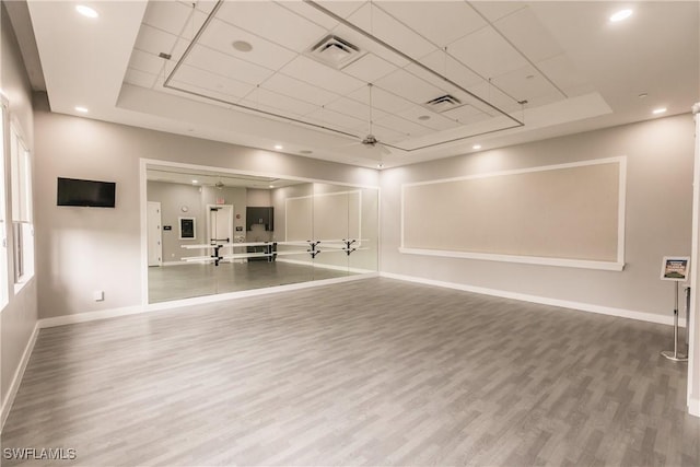 workout room featuring hardwood / wood-style floors, ceiling fan, and a tray ceiling