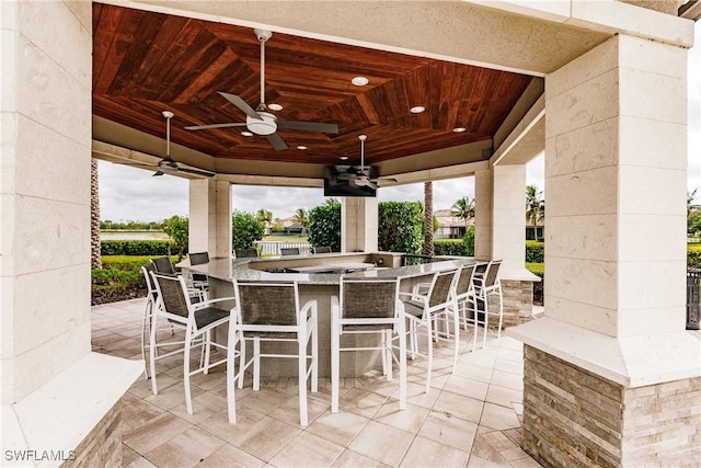 view of patio / terrace with ceiling fan and a bar