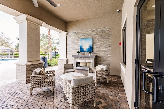 view of patio / terrace with ceiling fan and an outdoor fireplace