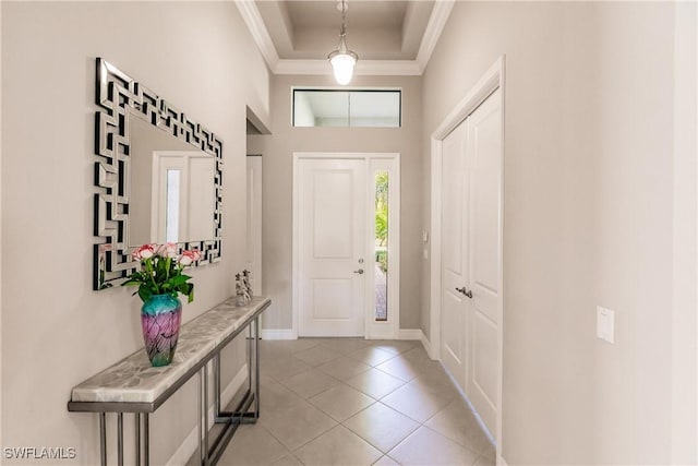 tiled entryway with a raised ceiling and ornamental molding