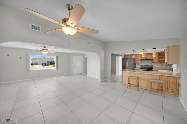 unfurnished living room with ceiling fan, sink, light tile patterned flooring, and vaulted ceiling