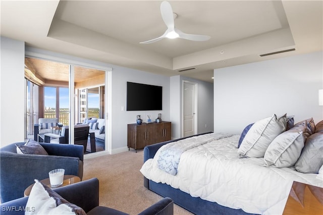 carpeted bedroom with a tray ceiling and ceiling fan