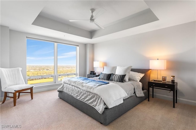 bedroom with carpet floors, a raised ceiling, and ceiling fan