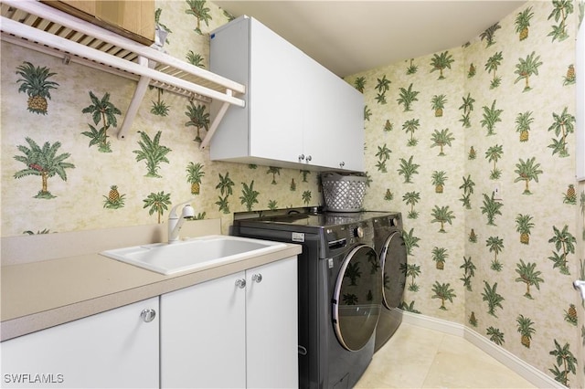 laundry room featuring cabinets, light tile patterned floors, sink, and washing machine and clothes dryer