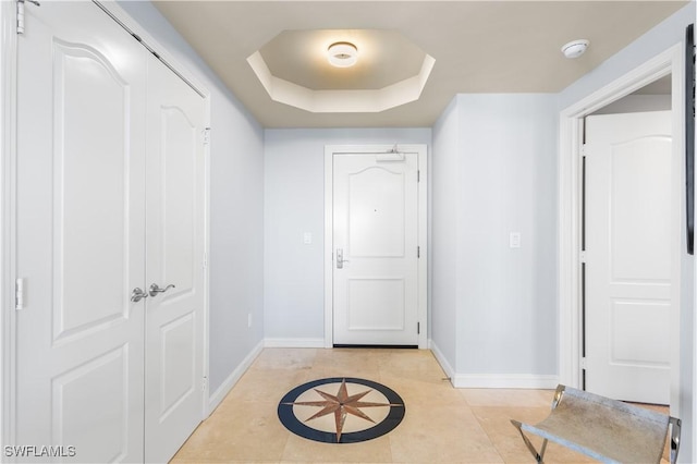 hallway with light tile patterned floors and a raised ceiling