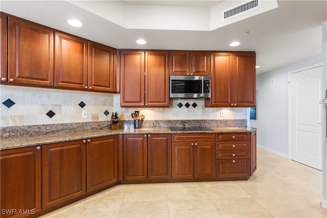 kitchen featuring stone counters, light tile patterned floors, backsplash, and black electric cooktop