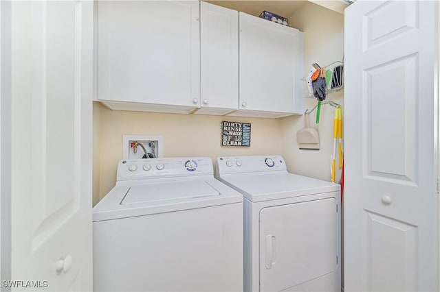 clothes washing area featuring washer and dryer and cabinets