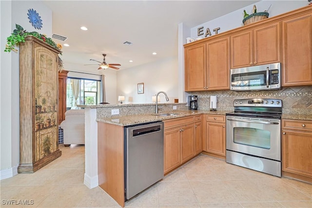 kitchen with kitchen peninsula, light stone countertops, stainless steel appliances, and ceiling fan