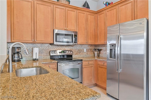 kitchen with backsplash, light stone countertops, sink, and appliances with stainless steel finishes