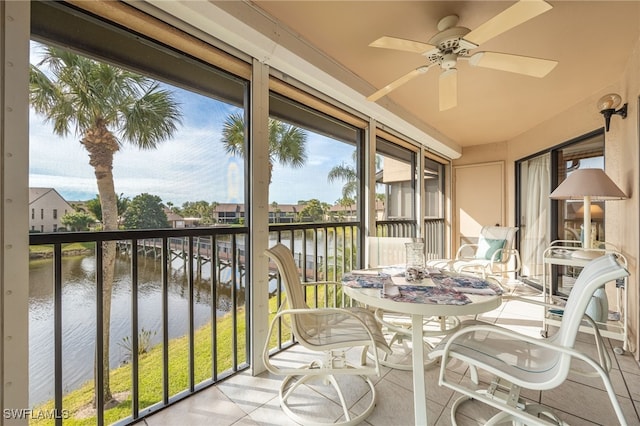 sunroom featuring ceiling fan and a water view