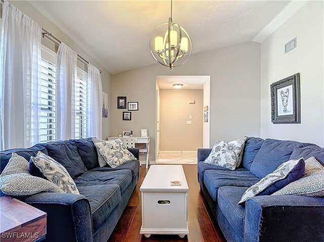 living room featuring dark hardwood / wood-style flooring, vaulted ceiling, and a notable chandelier