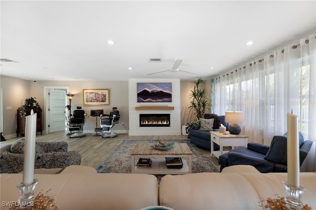 living area featuring light wood-style flooring, recessed lighting, a large fireplace, a ceiling fan, and visible vents