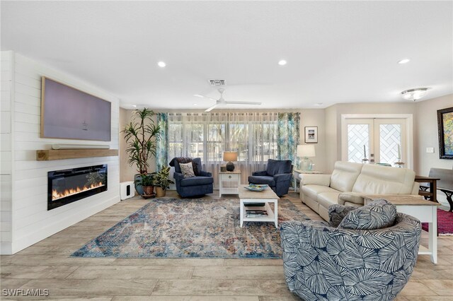 living room featuring ceiling fan, a fireplace, a wealth of natural light, and light hardwood / wood-style floors