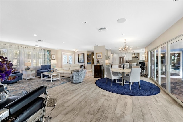 dining space with light wood-type flooring, visible vents, and an inviting chandelier