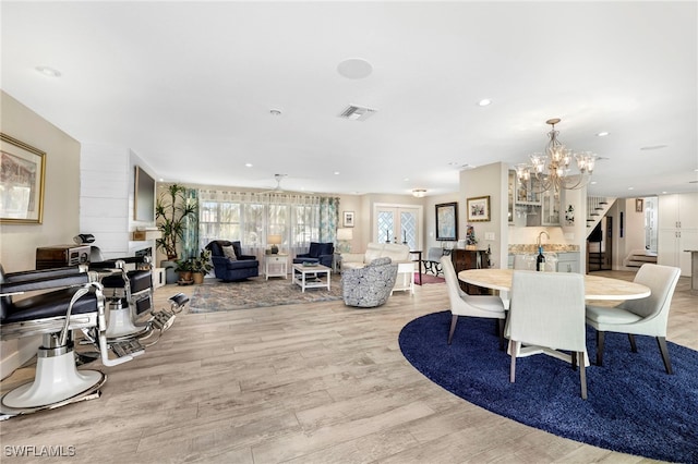 dining space featuring recessed lighting, visible vents, an inviting chandelier, light wood-type flooring, and stairs