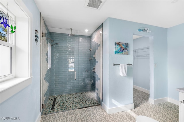 full bathroom featuring vanity, visible vents, baseboards, a stall shower, and a walk in closet