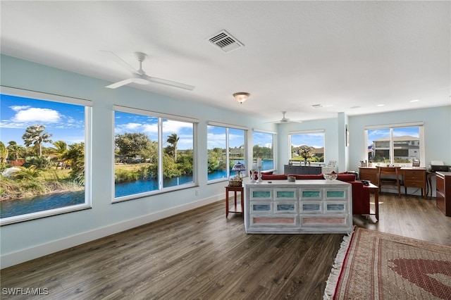 sunroom with ceiling fan, a water view, and visible vents