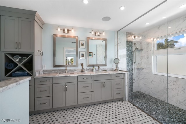 bathroom with double vanity, a marble finish shower, and a sink