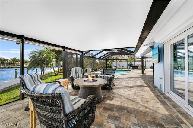 view of patio / terrace featuring an outdoor fire pit, a lanai, a water view, and an outdoor pool