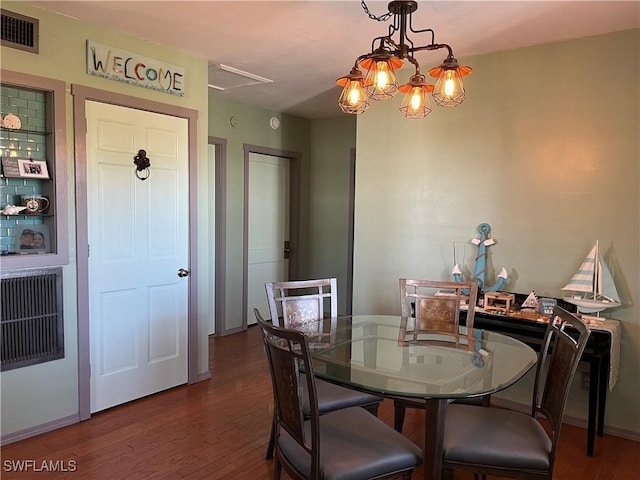 dining room with dark wood-type flooring and a notable chandelier