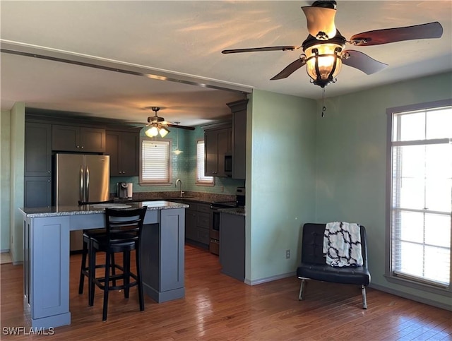 kitchen featuring plenty of natural light, a center island, dark hardwood / wood-style flooring, and appliances with stainless steel finishes