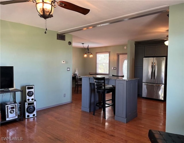 kitchen featuring a breakfast bar, a center island, stainless steel fridge, dark stone countertops, and a chandelier